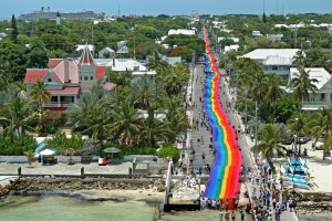 In this Sunday, June 15, 2003, file photo, flag carriers reach the Atlantic Ocean as they  finish spreading a 1 1/4-mile-long rainbow flag up and down Duval Street in Key West, Fla. The mammoth banner was created by Gilbert Baker and commemorated the 25th anniversary of the gay and lesbian icon that Baker, a San Francisco resident, conceived in 1978. The flag required 17,600 linear yards of fabric and weighed more than 5,000 pounds. (Andy Newman/Florida Keys News Bureau)