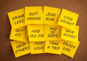 Sticky yellow note papers with a list of new year's resolutions on the cork bulletin board