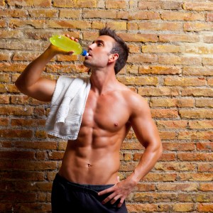 muscle shaped man at gym relaxed drinking energy drink