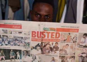 An AJWS grantee in Uganda shields his face with a local tabloid article, which incited public hatred and revealed the names and faces of LGBTI advocates. Some of them fear violence from homophobic extremists. PHOTO Evan Abramson