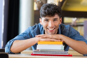 Young man leans on stack of books